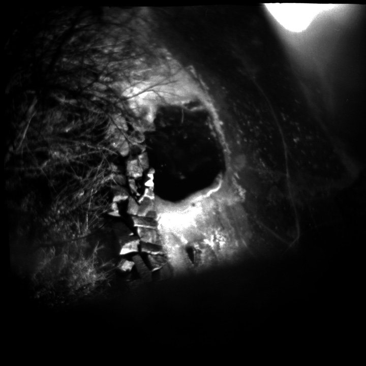 A dark hollow rimmed with faint light in grainy black and white — a void where the signal has cancelled to nothing.